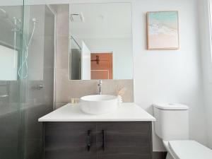 ein Badezimmer mit Waschbecken, Toilette und Spiegel in der Unterkunft Spacious Family Home 4B2B in Browns Plains in Browns Plains