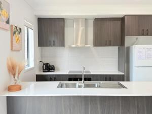 eine Küche mit einem Waschbecken und einer weißen Arbeitsplatte in der Unterkunft Spacious Family Home 4B2B in Browns Plains in Browns Plains + 12 Fotos