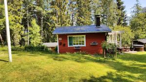 ein kleines rotes Haus inmitten eines Gartens in der Unterkunft Three cozy cottages, sauna and hot tub in Lohja + 28 Fotos