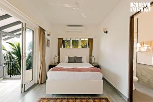 Un dormitorio con una cama blanca y una ventana grande. en StayVista at Di Mora by the Sea with Lawn & Pool, en Baga 28 fotos más