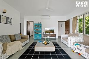 Una sala de estar con sofás y una mesa. en StayVista at Di Mora by the Sea with Lawn & Pool, en Baga