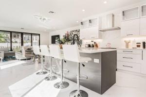 una cocina con armarios blancos y taburetes de barra blanca en Luxury Paradise walk to Las Olas -5 mins to Beach, en Fort Lauderdale 31 fotos más