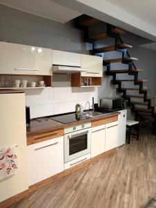 une cuisine avec des placards blancs et un escalier dans l'établissement Apartament dwupoziomowy Dom na patio Kościuszki self-check-in, à Katowice
