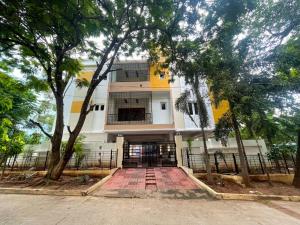 Un gran edificio blanco con árboles delante. en Arrow Service Appartment, en Gachibowli