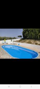 a large blue swimming pool next to a beach at Alojamiento rural El Yate in Montefrío +11 photos