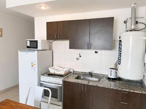 a kitchen with a white refrigerator and a sink at Loft frente al santorio de la mujer in Rosario
