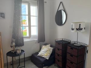 a room with a chair and a mirror and a window at Maisonnette à 30 mètres de la plage in Saint-Denis-dʼOléron