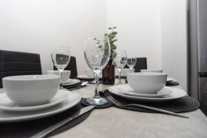 a table with plates and cups and wine glasses at Maple - Telford House - With Parking in Telford