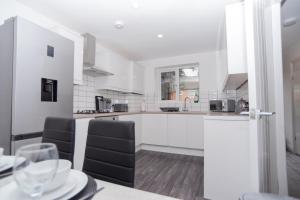 a kitchen with white cabinets and a table with chairs at Maple - Telford House - With Parking in Telford