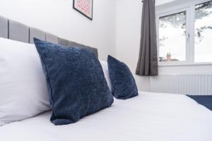a bed with two blue pillows on top of it at Maple - Telford House - With Parking in Telford +19 photos