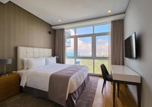 a bedroom with a bed and a desk and a large window at UH FLAT Hotels & Resorts in Iskandar Puteri