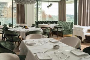 un ristorante con tavoli e sedie bianchi e finestre di New Belgrade Premium Hotel a Belgrado