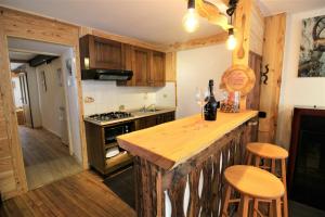 a kitchen with wooden cabinets and a counter with stools at Stone Cabin With Views Over Balme Valley in Ala di Stura