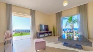 a living room with a tv and a large window at Aristea Apartments in Palaiochóra