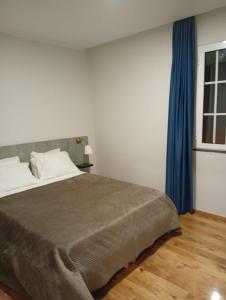 a bedroom with a bed with a blue curtain at Oak Tree House- Ponta do Pargo in Lombada Velha +23 photos