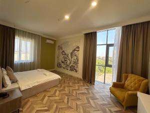 a bedroom with a bed and a chair and a window at Boutique Hotel "White HiLL" in Aktau