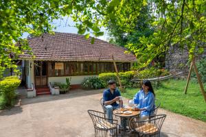 dos personas sentadas en una mesa frente a una casa en Ennexure by Raho, en Siddapur 11 fotos más