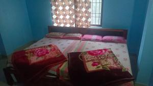 a bed with three pillows on it in a room at Amrutha Easy Stay in Kalasa