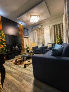 sala de estar con sofás azules y TV en Breezynest in Island Front -by Darysen, en Alaminos