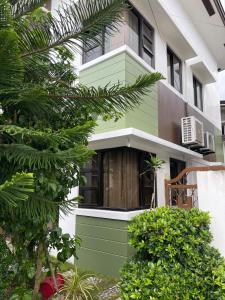 Una casa verde y blanca con árboles delante de ella. en Breezynest in Island Front -by Darysen, en Alaminos