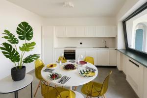 a white kitchen with a white table and yellow chairs at Casa Mimosa in Forio d'Ischia