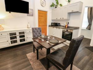 a kitchen with a table and two chairs and a kitchen with white cabinets at The Railway Apartment in Hexham +10 photos