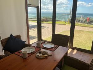 a wooden table with plates of food on it with a view of the ocean at Bay view sea cottage in Victoria Bay