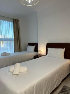 une chambre d'hôtel avec deux lits avec des draps blancs et une fenêtre dans l'établissement Jolie appt avec Balcon - Hypercentre, proche Medina et Plage, à Tanger 14 autres photos