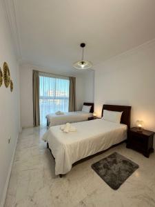 Un dormitorio con dos camas y una gran ventana. en Jolie appt avec Balcon - Hypercentre, proche Medina et Plage, en Tánger