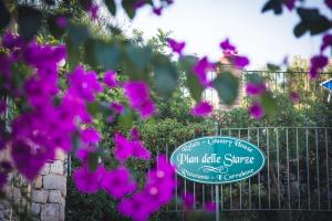a fence with purple flowers in front of a sign at Hotel Relais Pian delle Starze in Marina di Camerota +148 photos
