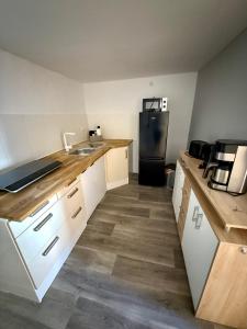 a kitchen with white cabinets and a black refrigerator at Retro und Gemütlichkeit im Fachwerkhaus - 2 Schlafzimmer, Wohnzimmer, Parkplatz, Balkon in Wolfhagen +6 photos
