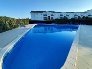 a blue swimming pool with chairs and buildings in the background at Résidence L'écume in Saint-Cyprien-Plage