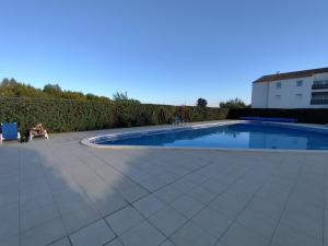 a person sitting in a chair next to a swimming pool at Résidence L'écume in Saint-Cyprien-Plage +7 photos