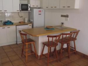 cocina con mesa con 4 sillas y nevera en Luuks, en Victoria Bay