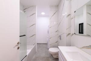 a white bathroom with a toilet and a sink at Levication Premium Private Jacuzzi Apartments in Tiberias +90 photos