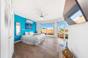 a bedroom with a bed and a blue wall at Beautiful 5BR Villa *Zen*Nature*Views*BBQ*BathTub* in Noord +44 photos