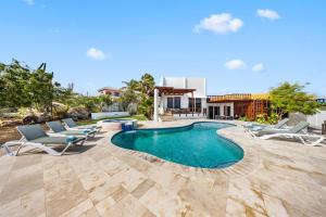 a swimming pool with lounge chairs and a house at Beautiful 5BR Villa *Zen*Nature*Views*BBQ*BathTub* in Noord