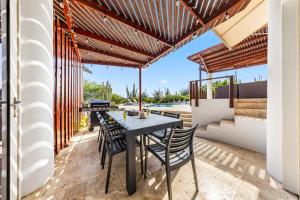 a patio with a table and chairs and a swimming pool at Beautiful 5BR Villa *Zen*Nature*Views*BBQ*BathTub* in Noord