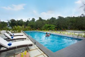 a woman is in a swimming pool with lounge chairs at The Grand Sanvika in Ramakkalmedu