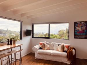 un salon avec un canapé et deux fenêtres dans l'établissement Floriana on Church - Oneroa, à Waiheke Island
