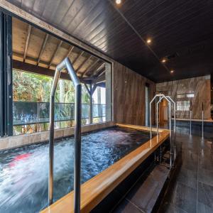 a hot tub in a room with a large window at Livemax Resort Inami Seafront in Inami