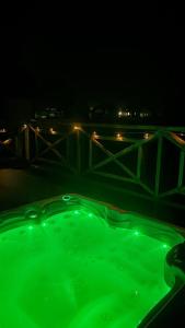 a green bath tub at night with lights in the background at Warmia Domek Bukowy in Woryty