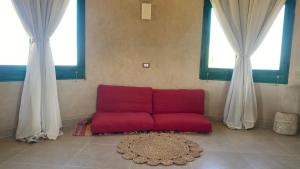 a red couch in a room with two windows at moon retreat in ‘Izbat Mushandid al Kabīrah