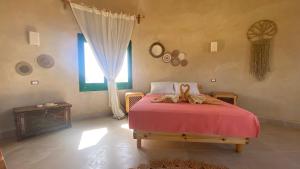 a bedroom with a bed with a red blanket and a window at moon retreat in ‘Izbat Mushandid al Kabīrah