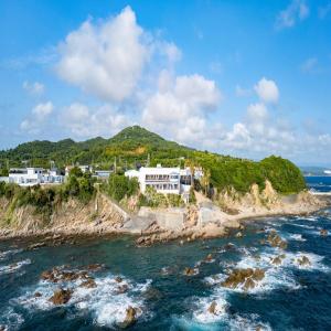 an island in the ocean with houses on a cliff at Livemax Resort Inami Seafront in Inami