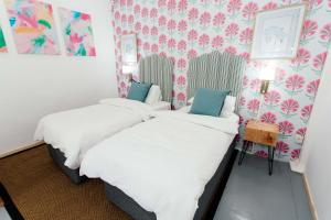 two beds in a room with floral wallpaper at 19 Mare St Apartments in Howick