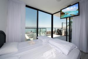 a bedroom with a large white bed with a large window at Levication Premium Private Jacuzzi Apartments in Tiberias