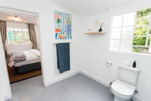 a white bathroom with a toilet and a bed at 19 Mare St Apartments in Howick +29 photos