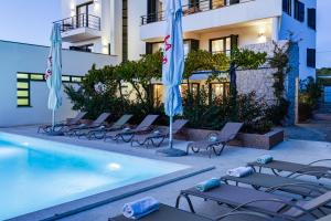 a hotel swimming pool with lounge chairs and umbrellas at Villa Paradise in Zadar with 6 bedrooms, pool and gaming room in Zadar