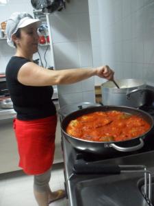 a woman in a kitchen stirring a pot of food at Osteria B&B Il Rifugio in Peschici